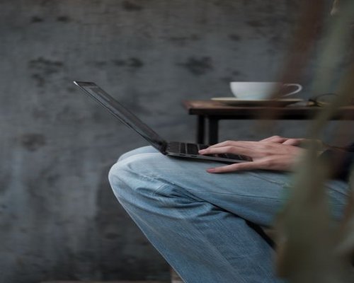 A person typing on a laptop at a modern cafe in Delhi